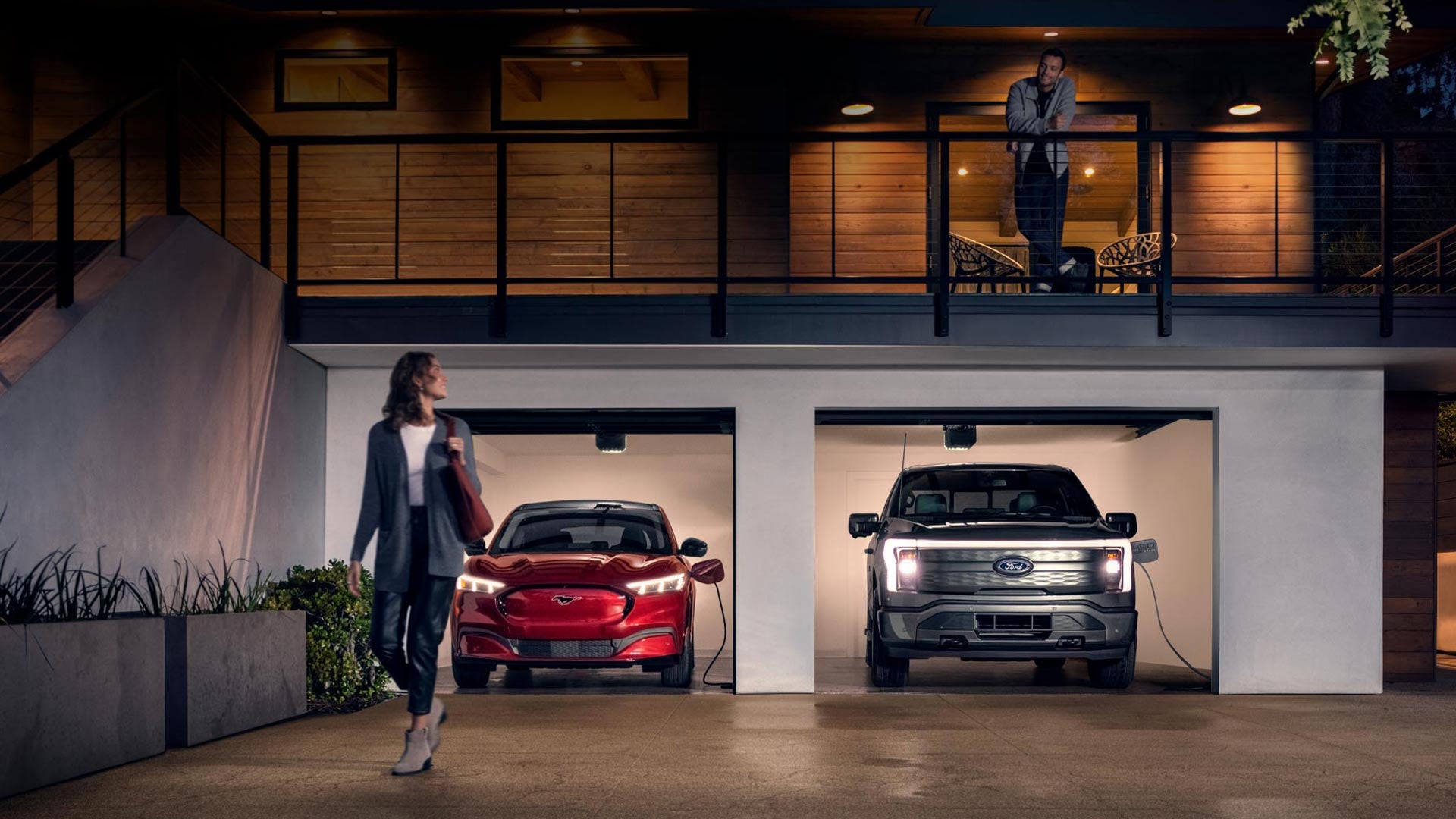 Woman walking out from home garage with a 2024 Mustang® Mach-E and Ford Lightning® truck in plugged-in and charging | Crain Ford Jacksonville in Jacksonville AR